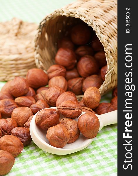 Hazelnuts, wooden spoon and basket on kitchen table