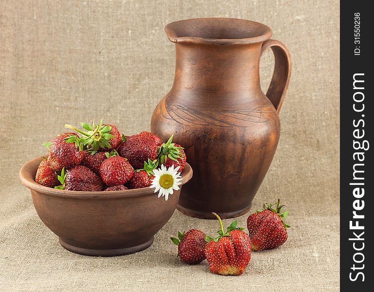 Rustic still life of strawberries in the clay pot