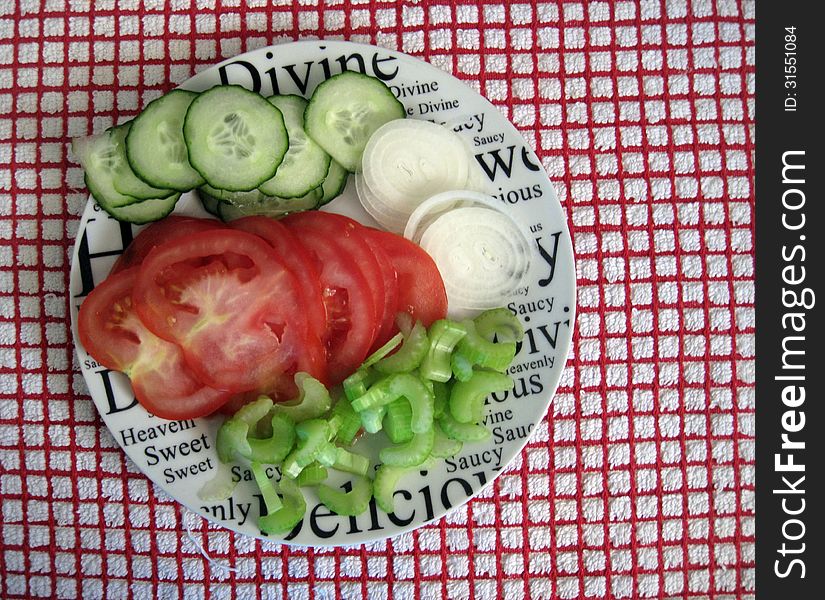 Raw uncooked Onions, cucumber, tomatoes, celery. On a plate. Raw uncooked Onions, cucumber, tomatoes, celery. On a plate.
