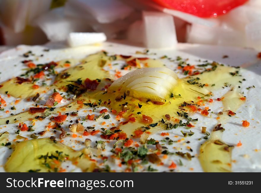 Feta cheese cut in slices, with fresh vegetables, dry herb spices and olive oil - the ingredients for a healthy greek salad. Feta cheese cut in slices, with fresh vegetables, dry herb spices and olive oil - the ingredients for a healthy greek salad