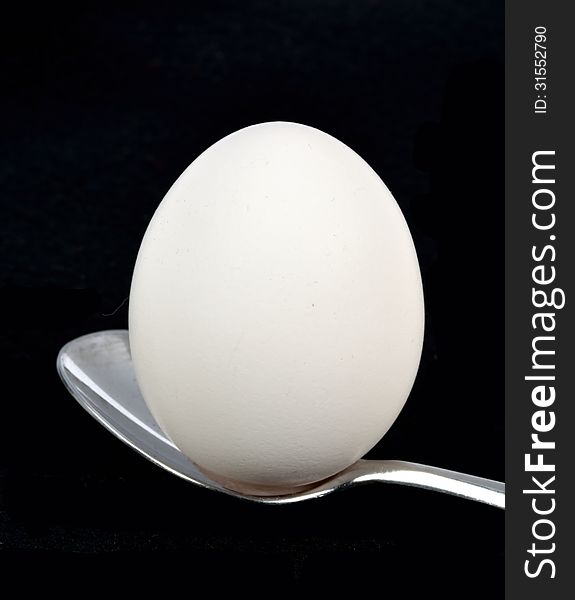 An egg on a spoon on a black background. An egg on a spoon on a black background.