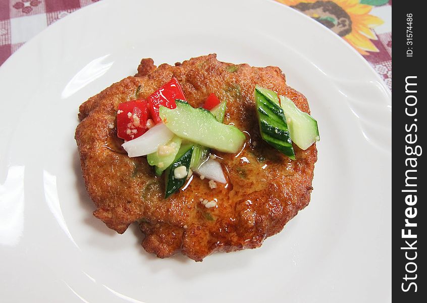 A single nugget with sweet sauce and vegetables served on a white plate.