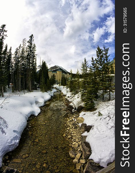 Stream with The Fairmont Chateau Lake Louise and rockies in the background thru fisheye lens