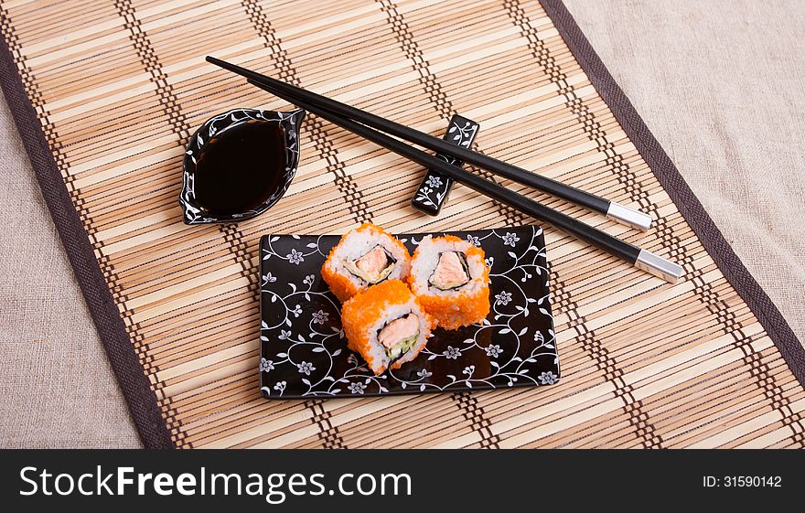Japanese food - rolls with salmon on a wicker napkin with Japanese equipment