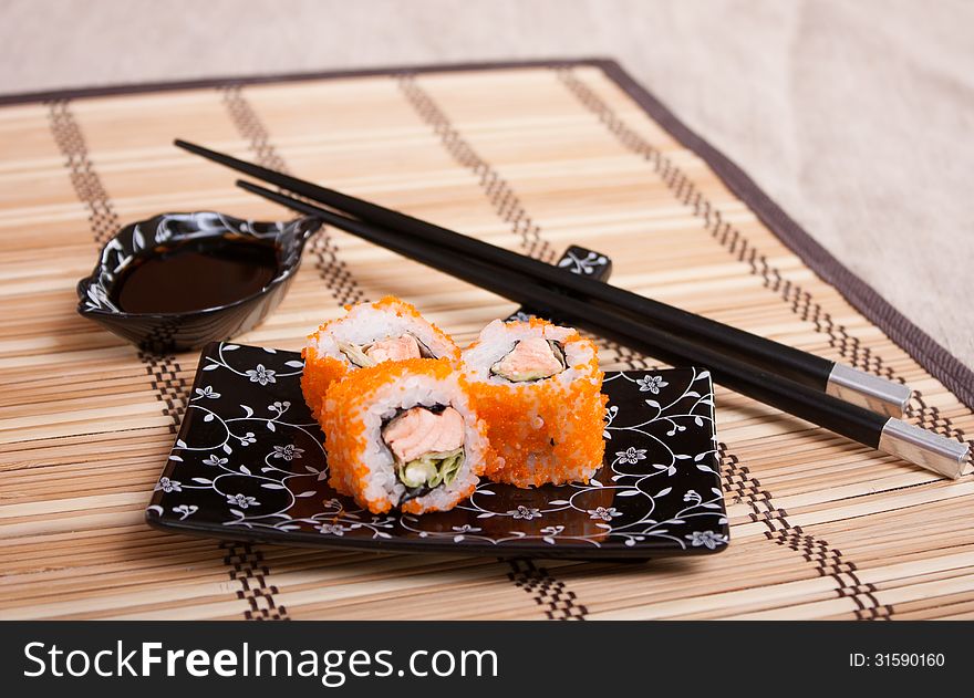 Japanese food - rolls with salmon and caviar on kappelana wicker napkin with Japanese equipment