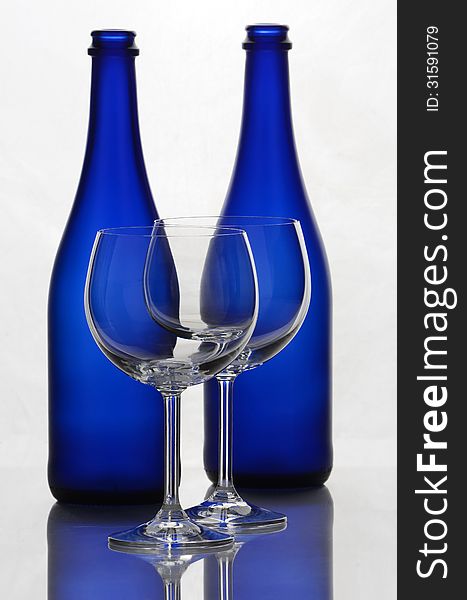 Color wine bottles and wine glasses on a white background with reflections