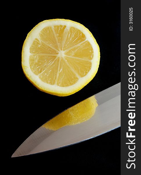 Cut lemon and blade of knife on black background. Cut lemon and blade of knife on black background
