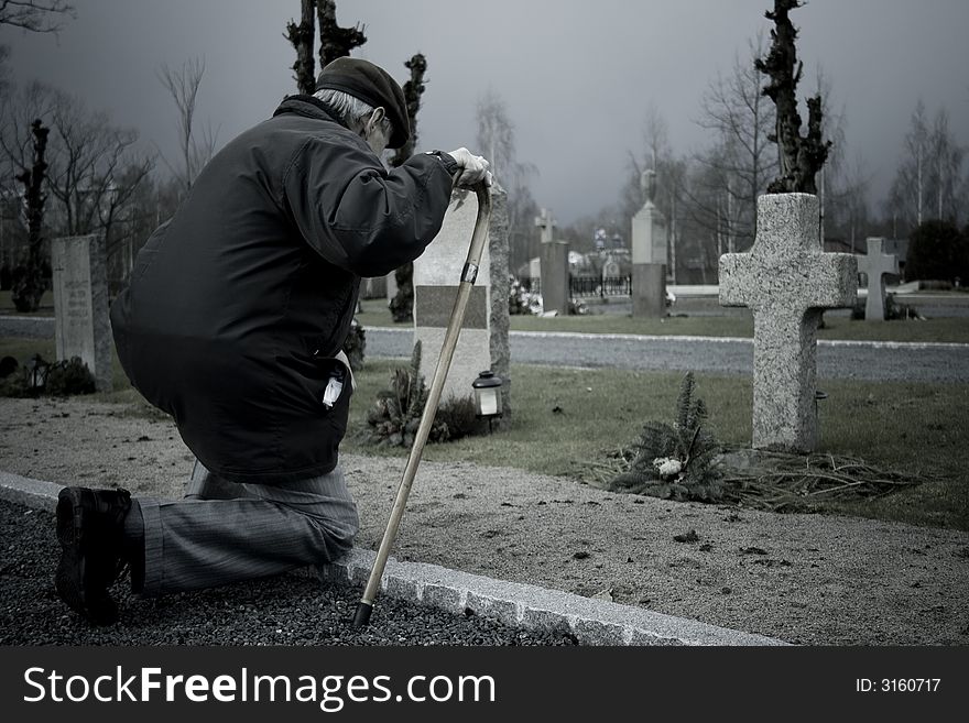 A man mourning the loss of his relative on the cemetery. A man mourning the loss of his relative on the cemetery.