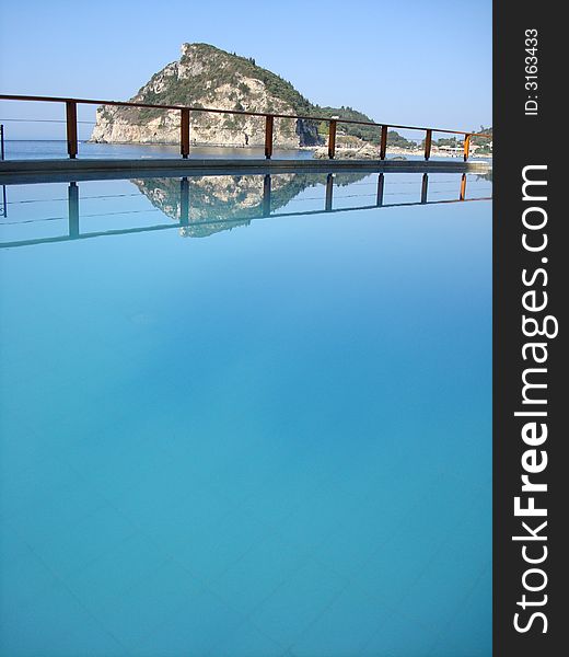 A reflection of one of the hills in Paleokastritsa in a swimming pool by the beach. A reflection of one of the hills in Paleokastritsa in a swimming pool by the beach.