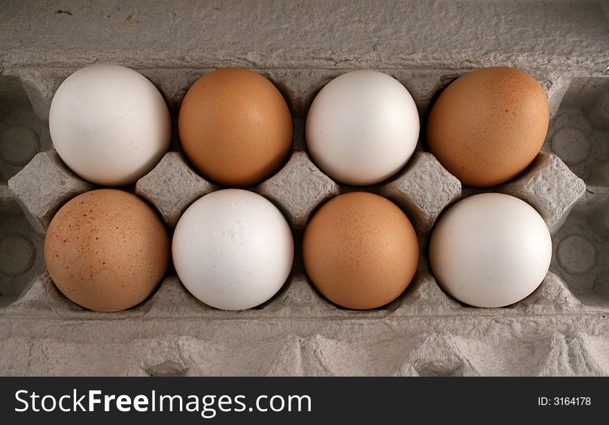 A carton of alternating brown and white eggs, from overhead. A carton of alternating brown and white eggs, from overhead