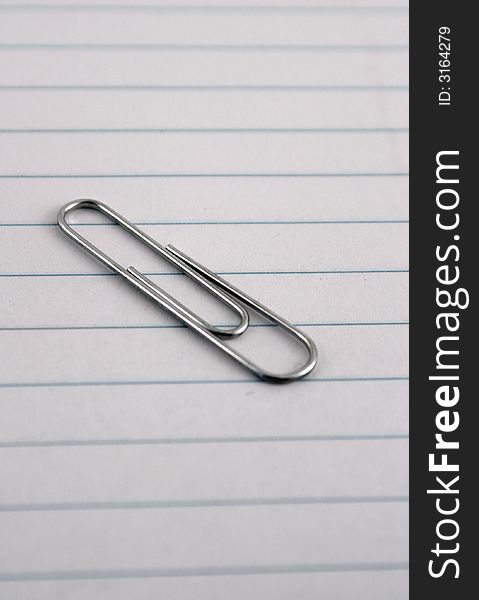 A single paperclip on a piece of lined paper