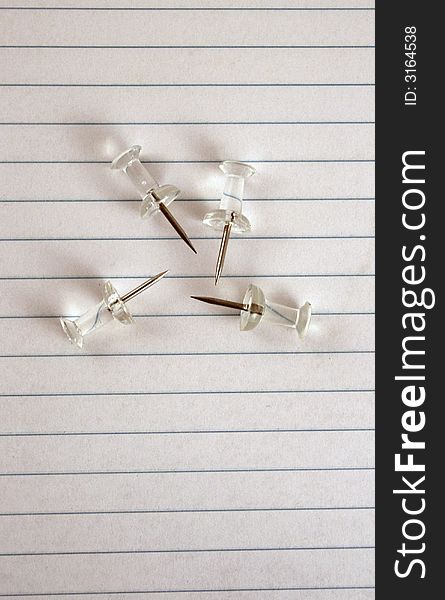 A group of thumbtacks on a piece of lined paper