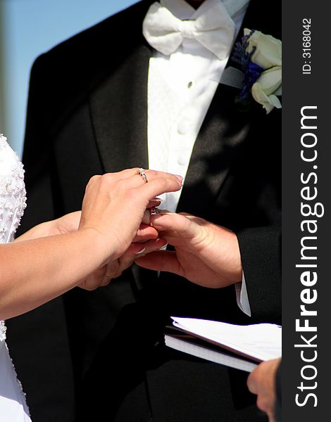 Close up of Bride placing the ring on grooms finger. Close up of Bride placing the ring on grooms finger