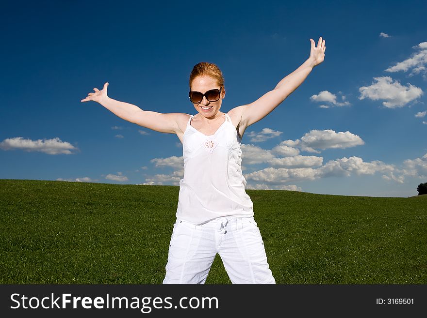 Woman on green meadow, happy and free. Grass going to the horizon, blue sky with clouds. Summery. Woman on green meadow, happy and free. Grass going to the horizon, blue sky with clouds. Summery