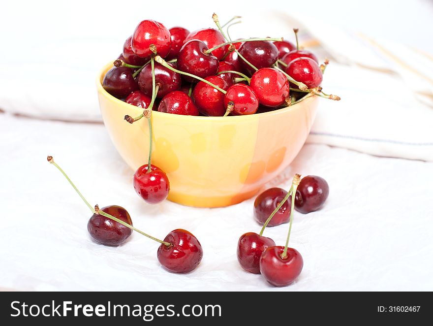 Ripe cherries in a yellow plate on the table