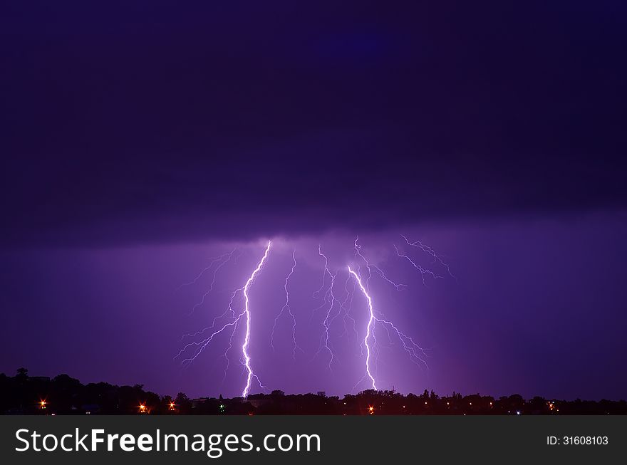 Lightning on the background of dark blue, purple clouds in the city