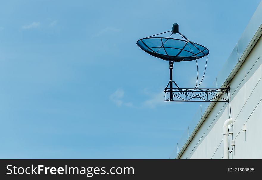 Black satellite dish on roof against blue sky