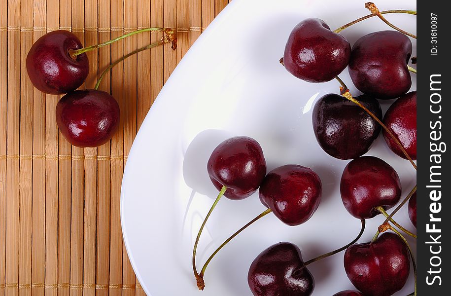 Sweet cherries in water drops on white plate