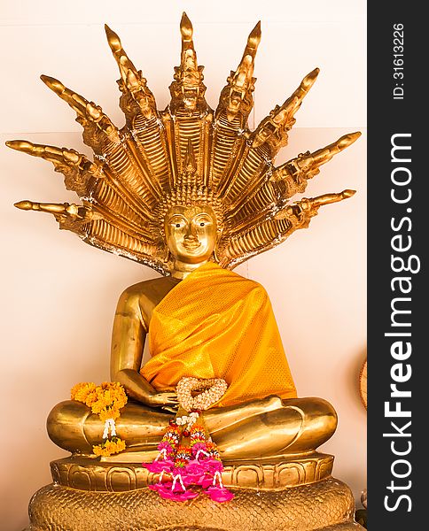 Golden buddha with naga behind and flower worship