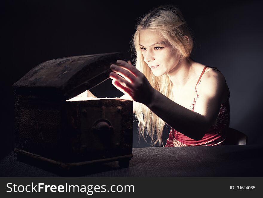 Young blond woman securing her treasure in a retro wooden chest. Young blond woman securing her treasure in a retro wooden chest