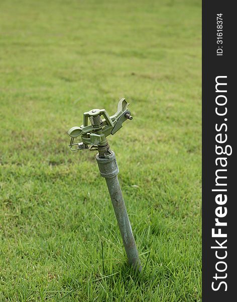 Water sprinkler in green lawn