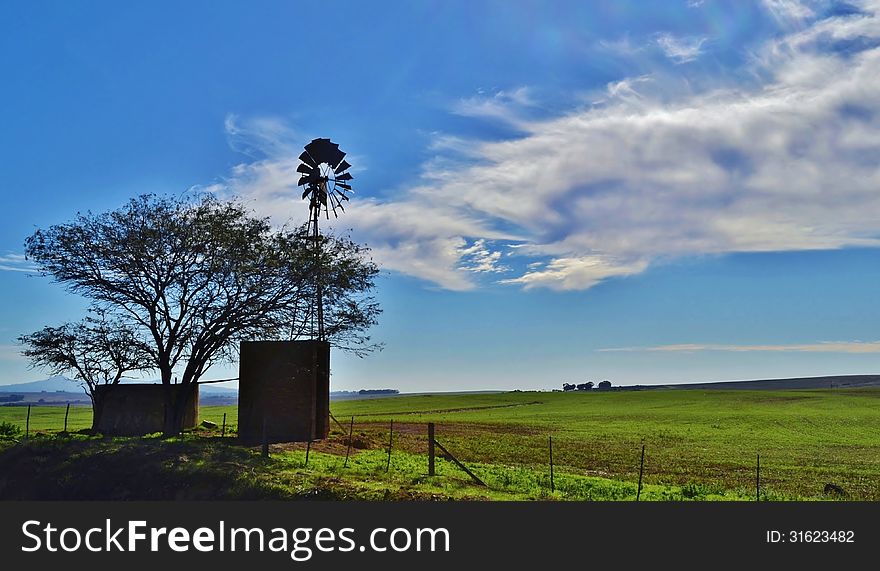 Landscape with waterpump windmill on meadow