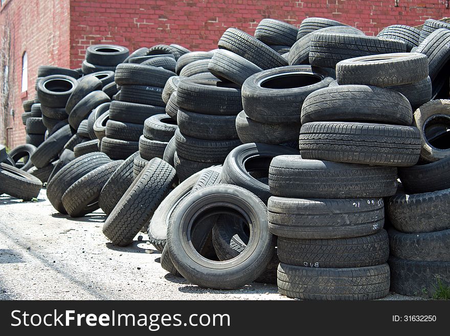 Pile of old used tires for recycling stacked in an alley. Pile of old used tires for recycling stacked in an alley