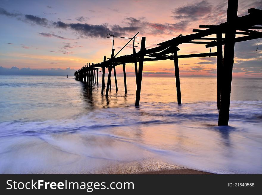 Old wooden bridge in the sea with sunset