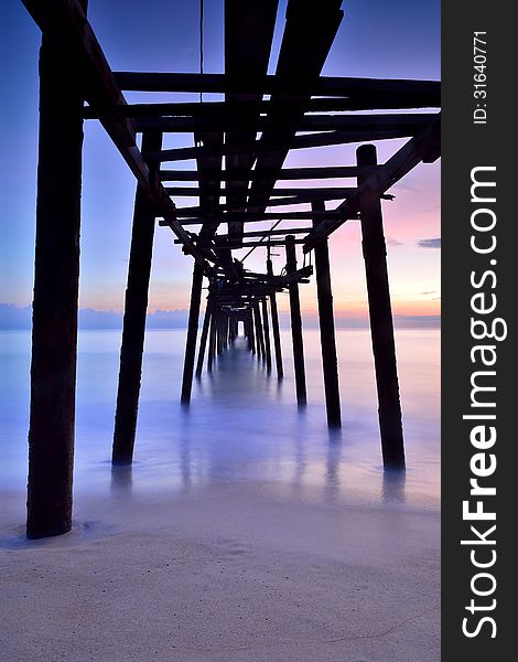 Old wooden bridge in the sea with sunset