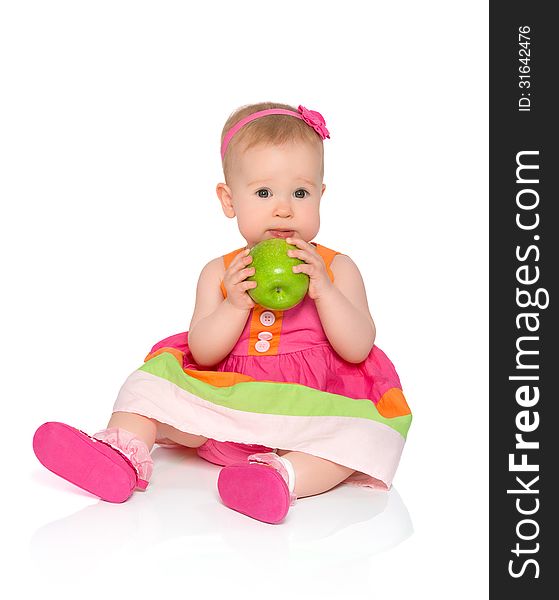 Happy little baby girl in bright multicolored festive dress with green apple isolated on a white background