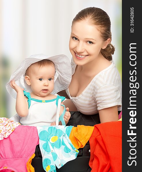 Mother and baby girl with suitcase and clothes ready for traveli