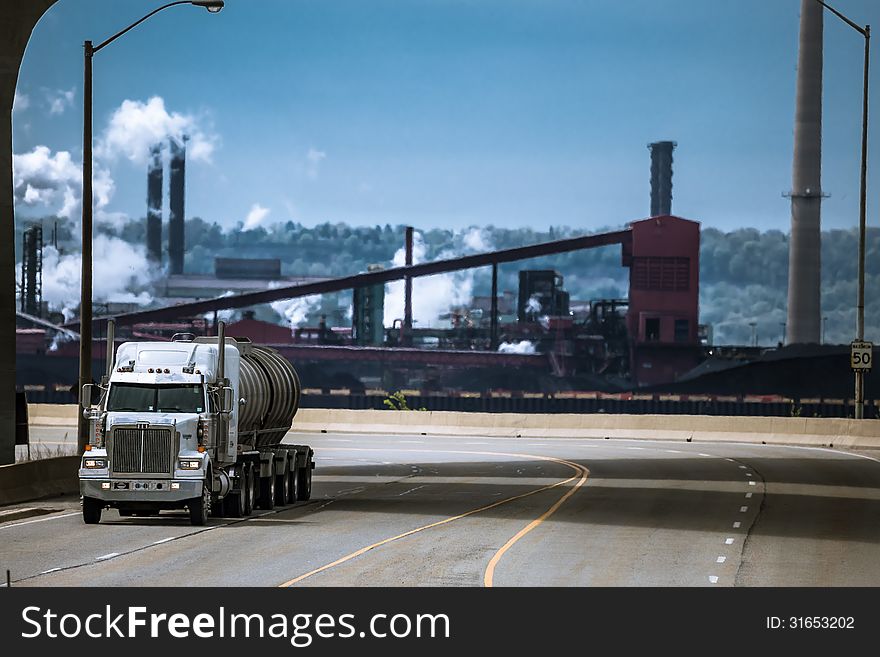 The heavy truck running from the industrial plant on the background. The heavy truck running from the industrial plant on the background