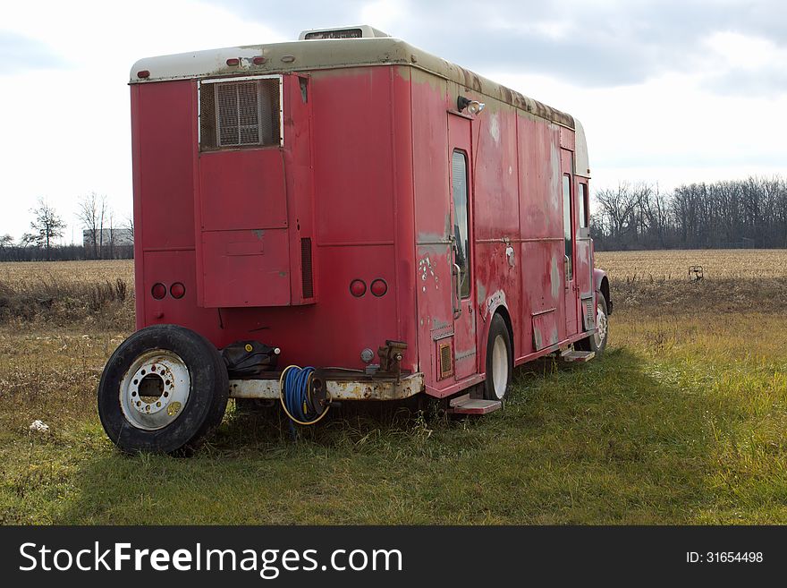 An old red and white camper trailer sitting in a field. An old red and white camper trailer sitting in a field