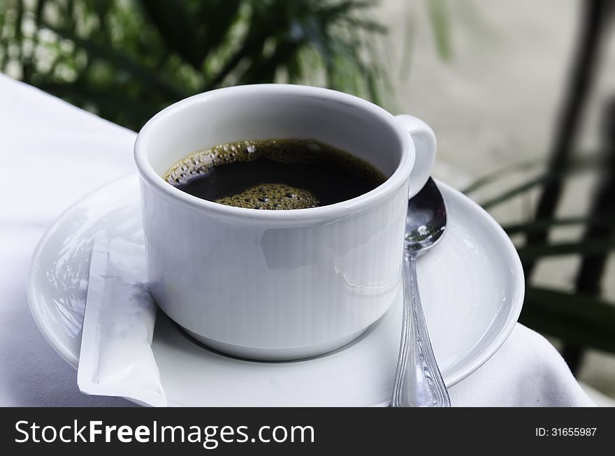 Black coffee with white table and tree background