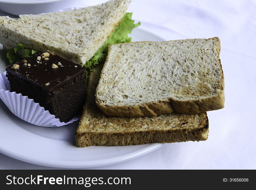 Baked bread and cake on plate and white table. Baked bread and cake on plate and white table