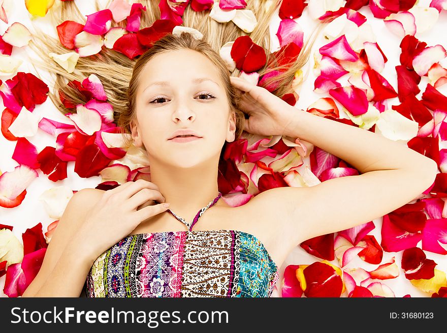 Young girl lies in the petals of roses, background