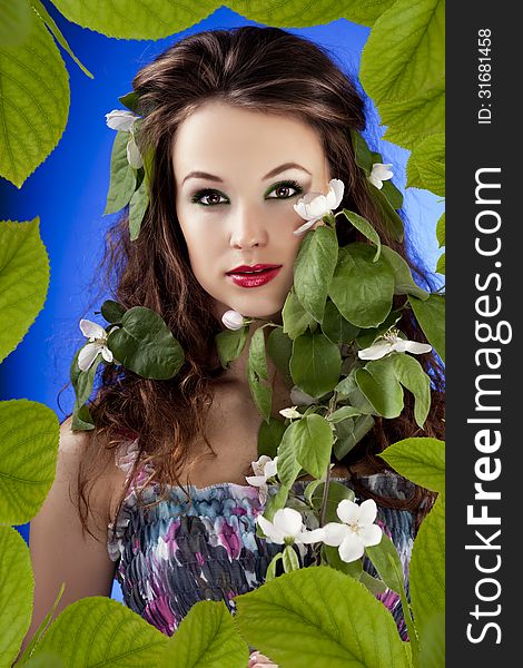 Beautiful glamour girl in leafs frame with flowers in hair