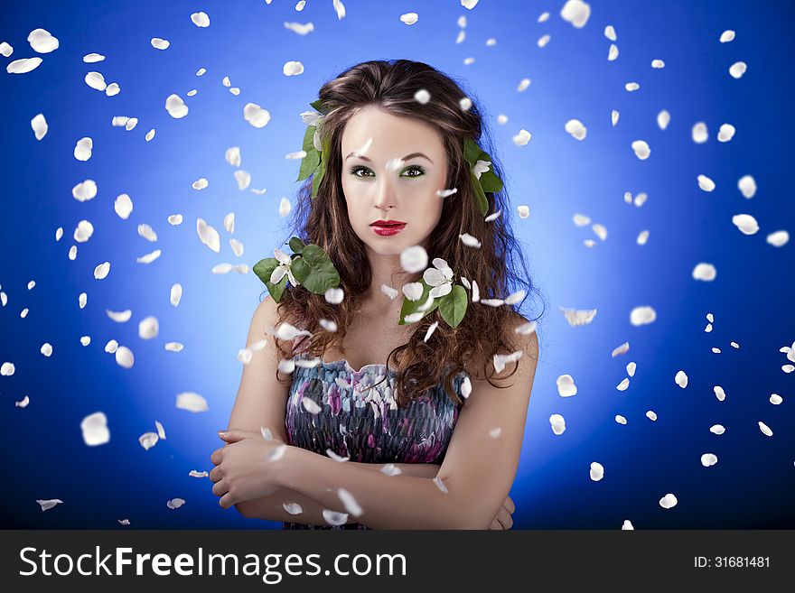 Gorgeous girl with flowers in hair and with flying petals around
