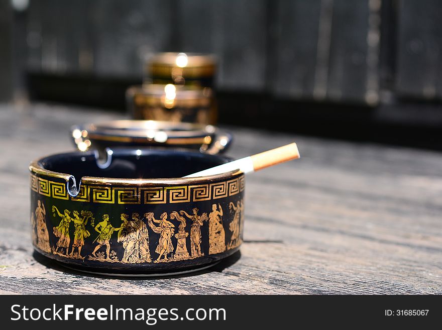 Cigarette in ashtray with Greek motifs. Cigarette in ashtray with Greek motifs