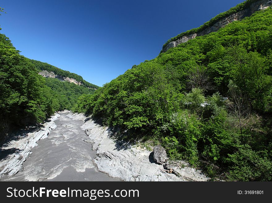 Rapid river narrow mountain path in Russia - Republic of Adygea. Sunny and clear day