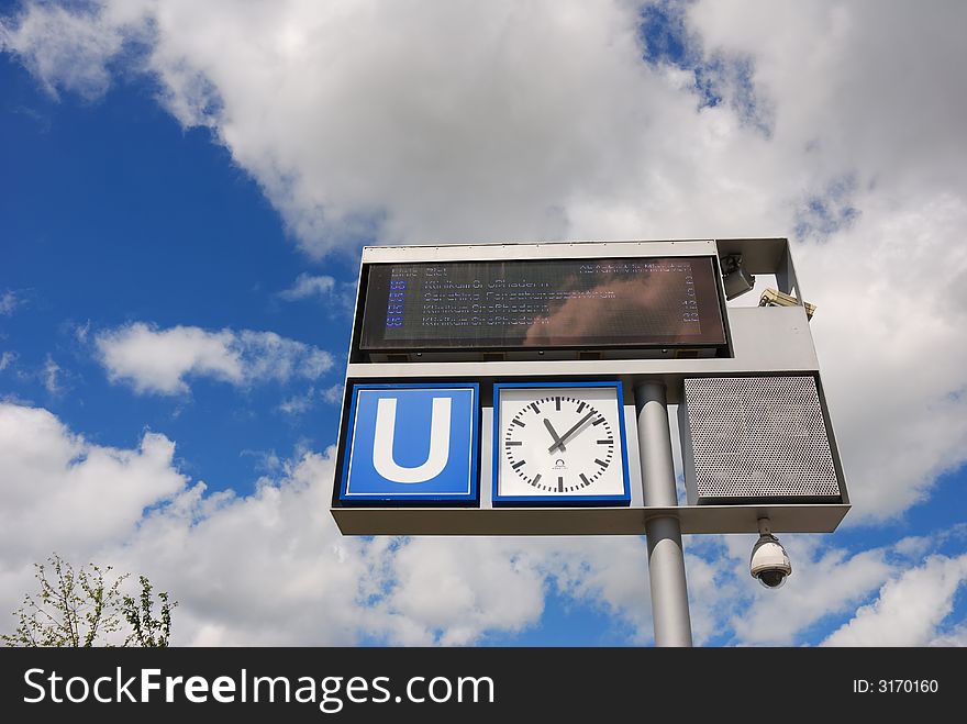 Subway sign with clock against sky