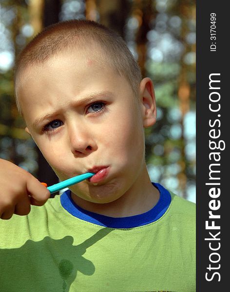 Nearly 5 years young boy is brushing his teeth in forest