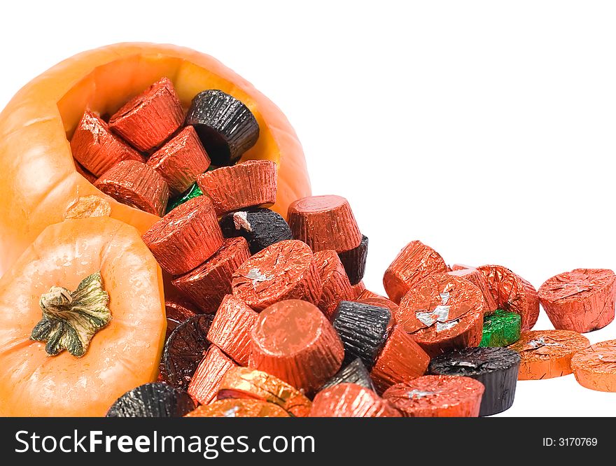 Pumpkin with top cut out spilling wrapped candy. Pumpkin with top cut out spilling wrapped candy