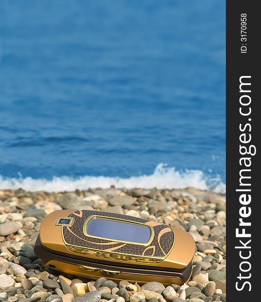 Mobile phone on beach, sea on background