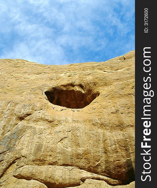 Blue sky and fluffy clouds above beautiful sandstone cliff with enticing round cave. Blue sky and fluffy clouds above beautiful sandstone cliff with enticing round cave