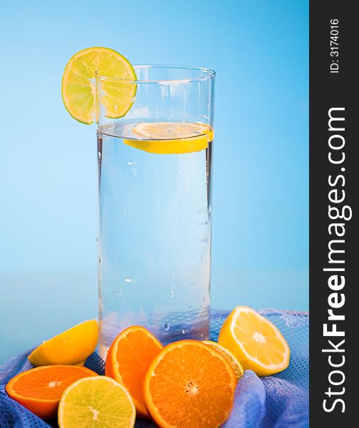 Oranges and lemons in transparent glass over blue background