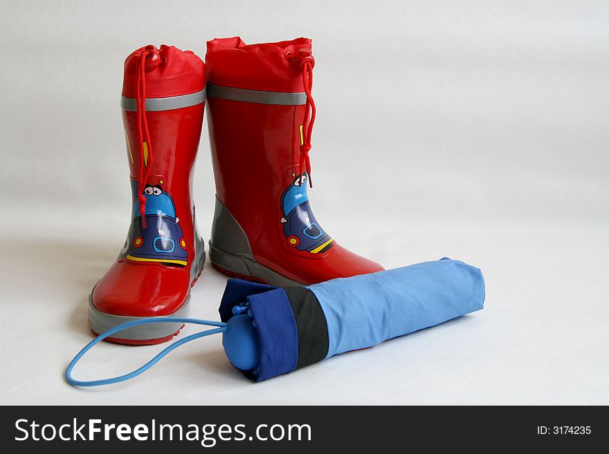 Red wellington boots and blue umbrella isolated on white background