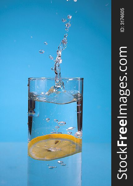 Lemon splash in transparent glass over blue background