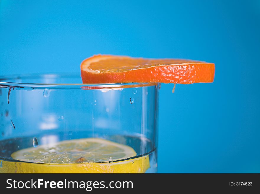 Oranges and lemons in transparent glass over blue background