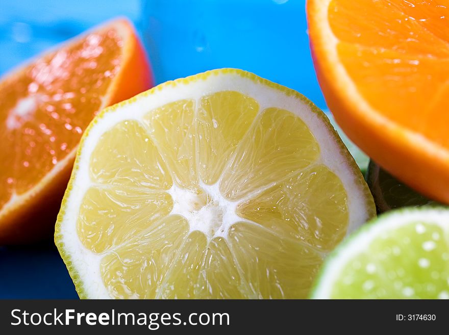 Oranges and lemons in transparent glass over blue background